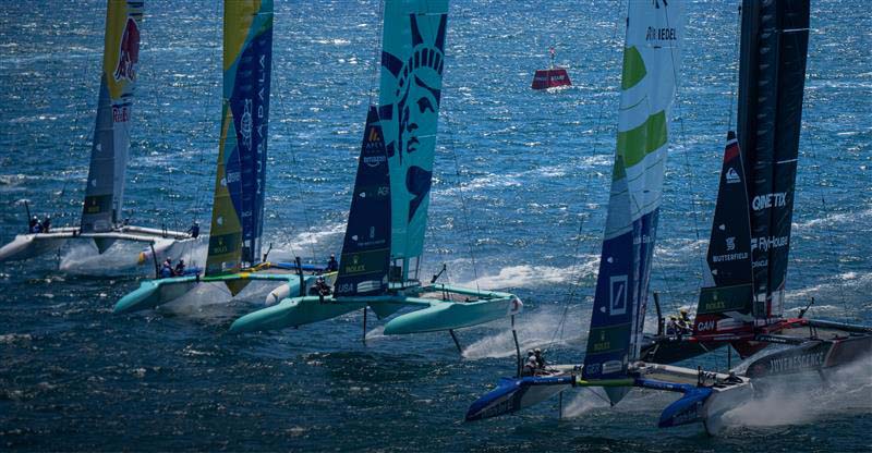 Tommy Hilfiger sailboats racing on choppy water with multiple colorful sails in the background