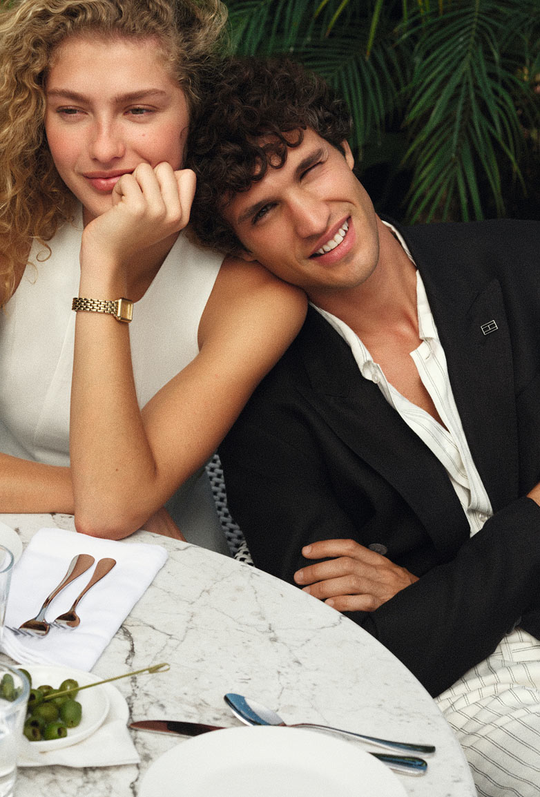 A couple sitting at a table wearing Tommy Hilfiger products
