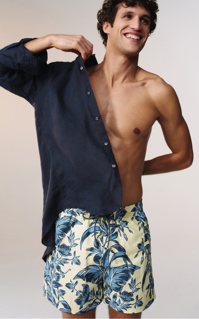Male model wearing a Tommy Hilfiger swim short and navy shirt