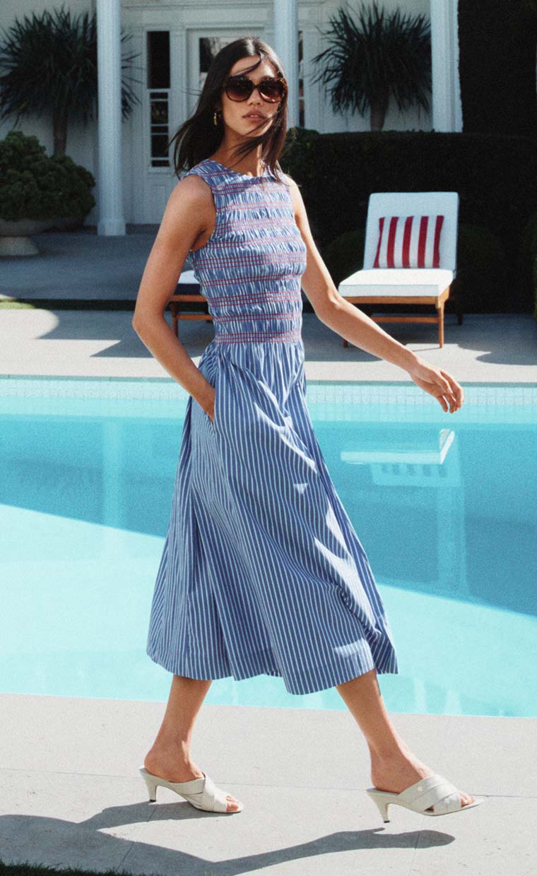 Woman walking poolside wearing a Tommy Hilfiger blue striped summer dress.