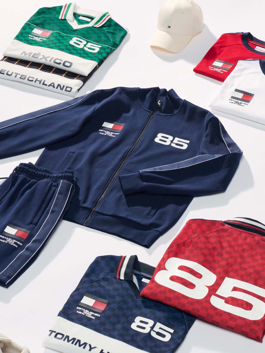 Folded sporty Tommy Hilfiger apparel and accessories displayed together, including bags and clothing.