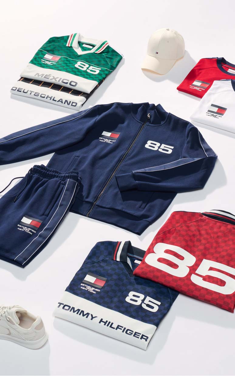 Folded sporty Tommy Hilfiger apparel and accessories displayed together, including bags and clothing.