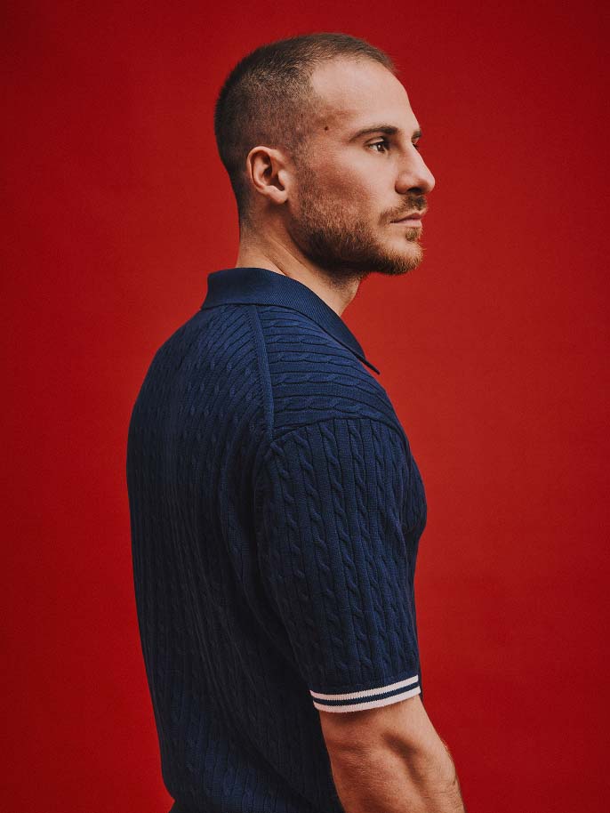 Liverpool player Alexis Mcallister wearing Tommy Hilfiger with a red background.