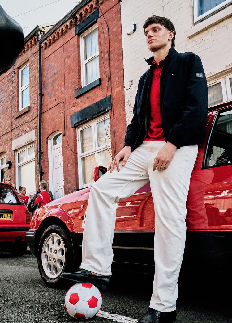 Liverpool player Giovanni Leoni leans against a red car wearing a Tommy Hilfiger red polo shirt and white chinos.