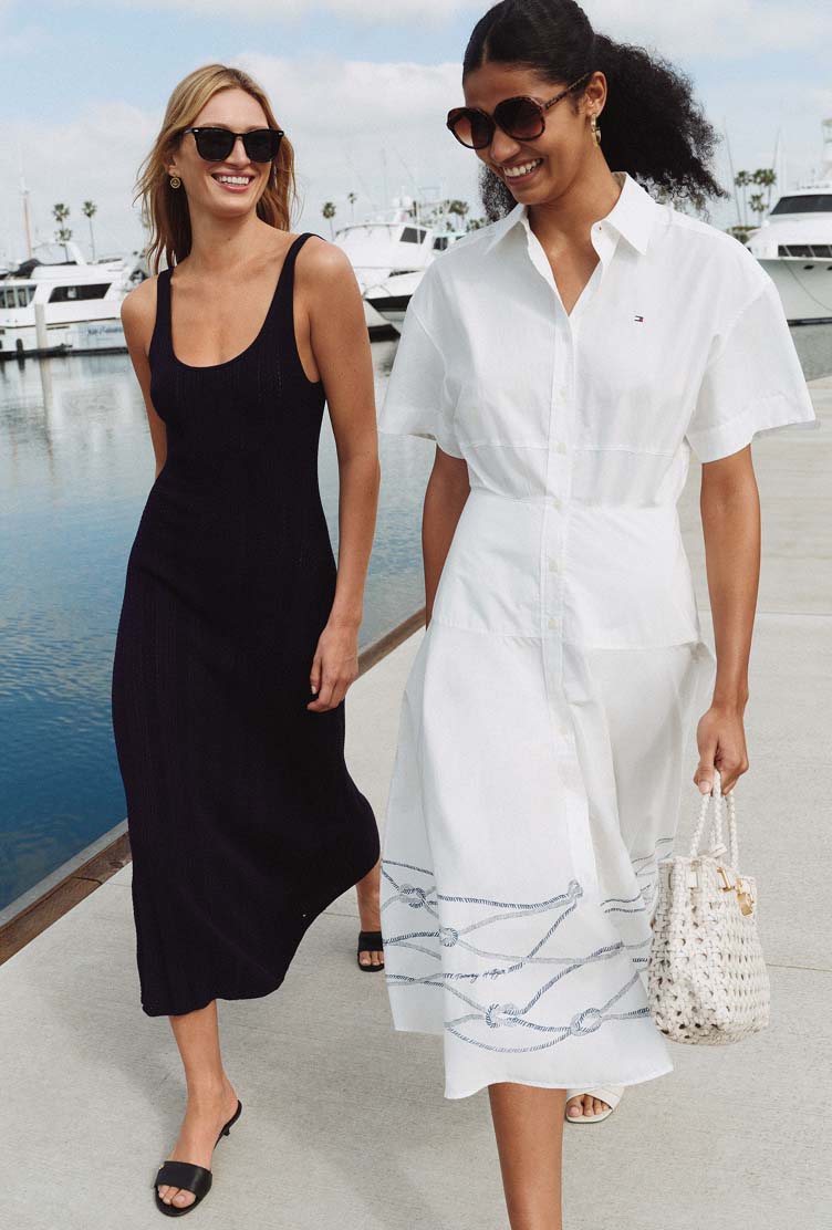 Two models walking together in coordinated white and navy Tommy Hilfiger summer outfits.