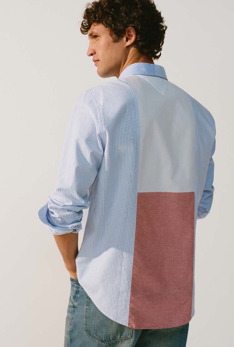 Male model wearing a Tommy Hilfiger color-block button-down shirt in light blue, white, and muted red.