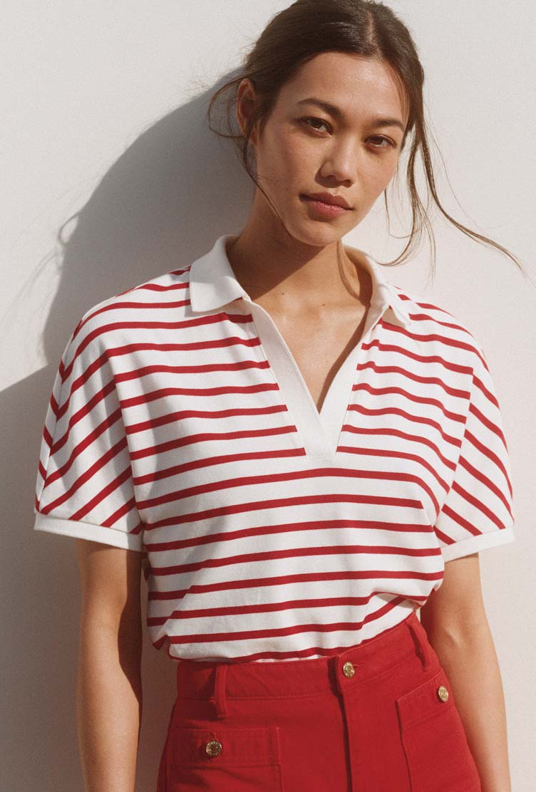 Blonde model wearing a Tommy Hilfiger navy, white, and red striped sleeveless knit top.