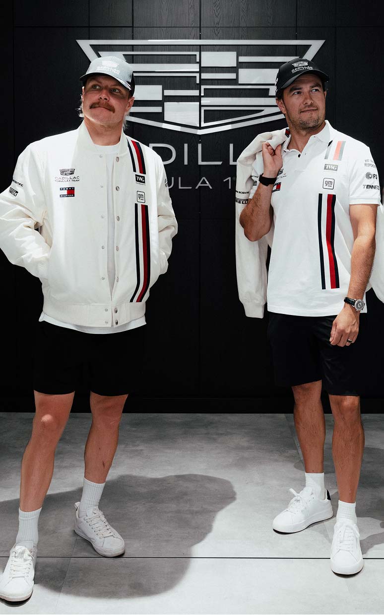 Two models posing in branded racing-inspired outfits, one seated and one standing.