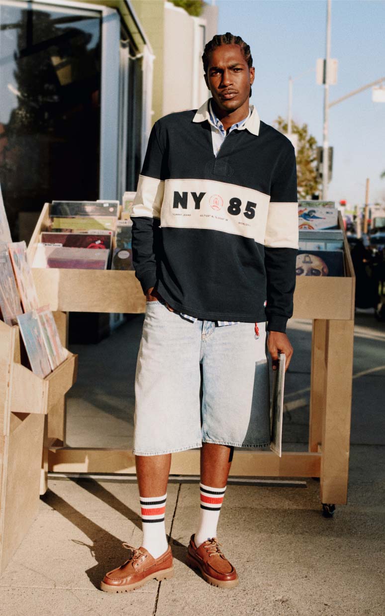 Male model wearing a navy-and-white Tommy Jeans pullover with shorts and striped socks.