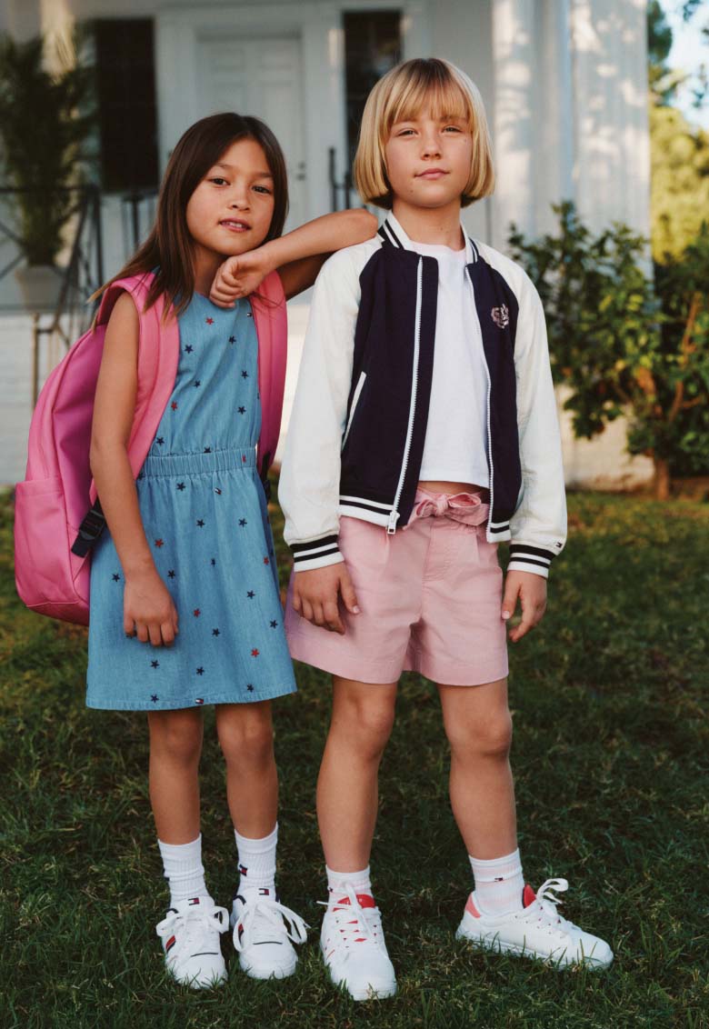 Children outdoors wearing Tommy Hilfiger clothing and backpacks.