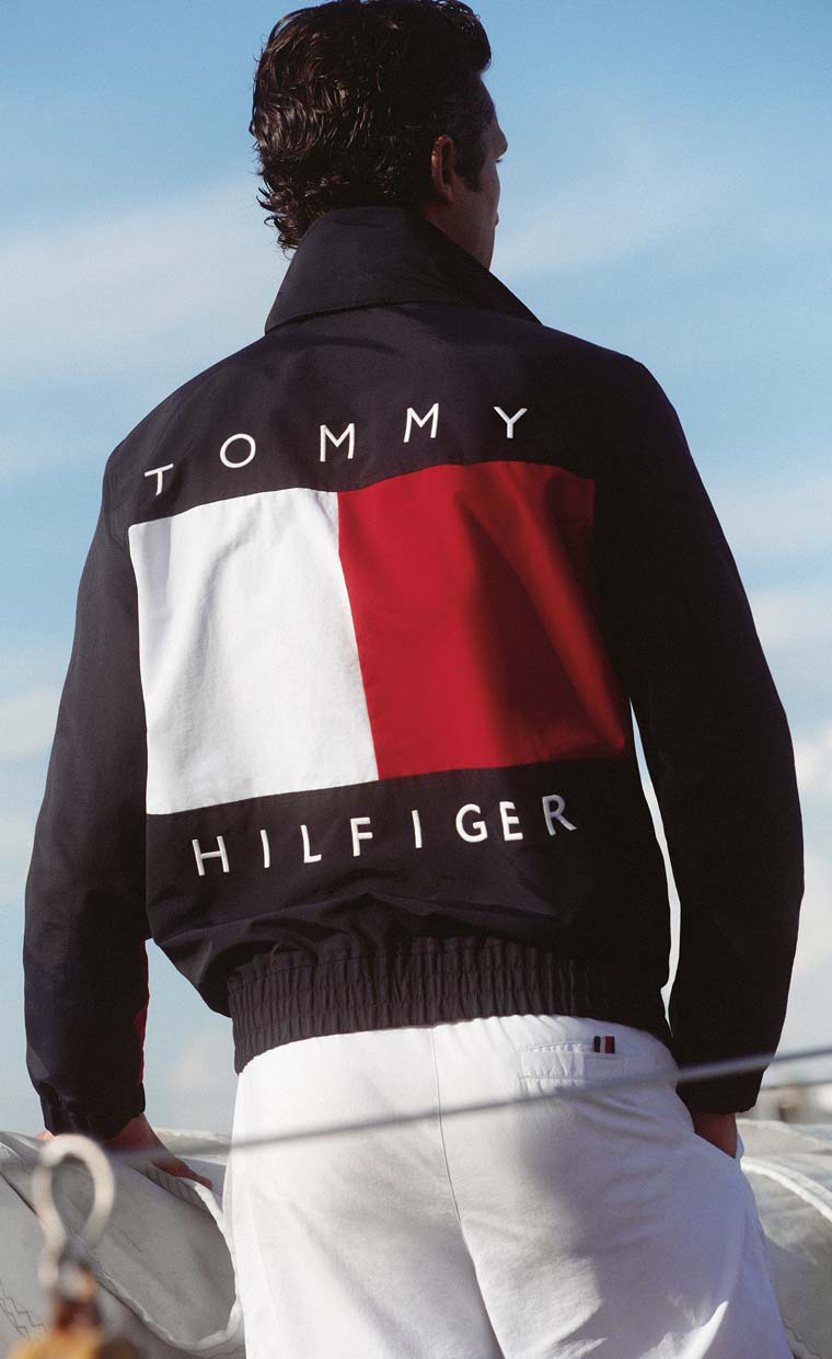 Model wearing a Tommy Hilfiger color-block jacket viewed from the back outdoors.
