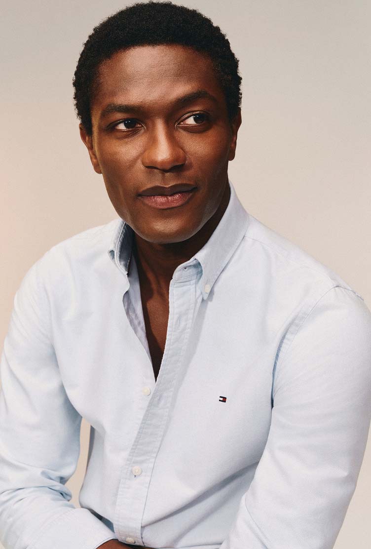 Model wearing a light blue Tommy Hilfiger button-down Oxford shirt.