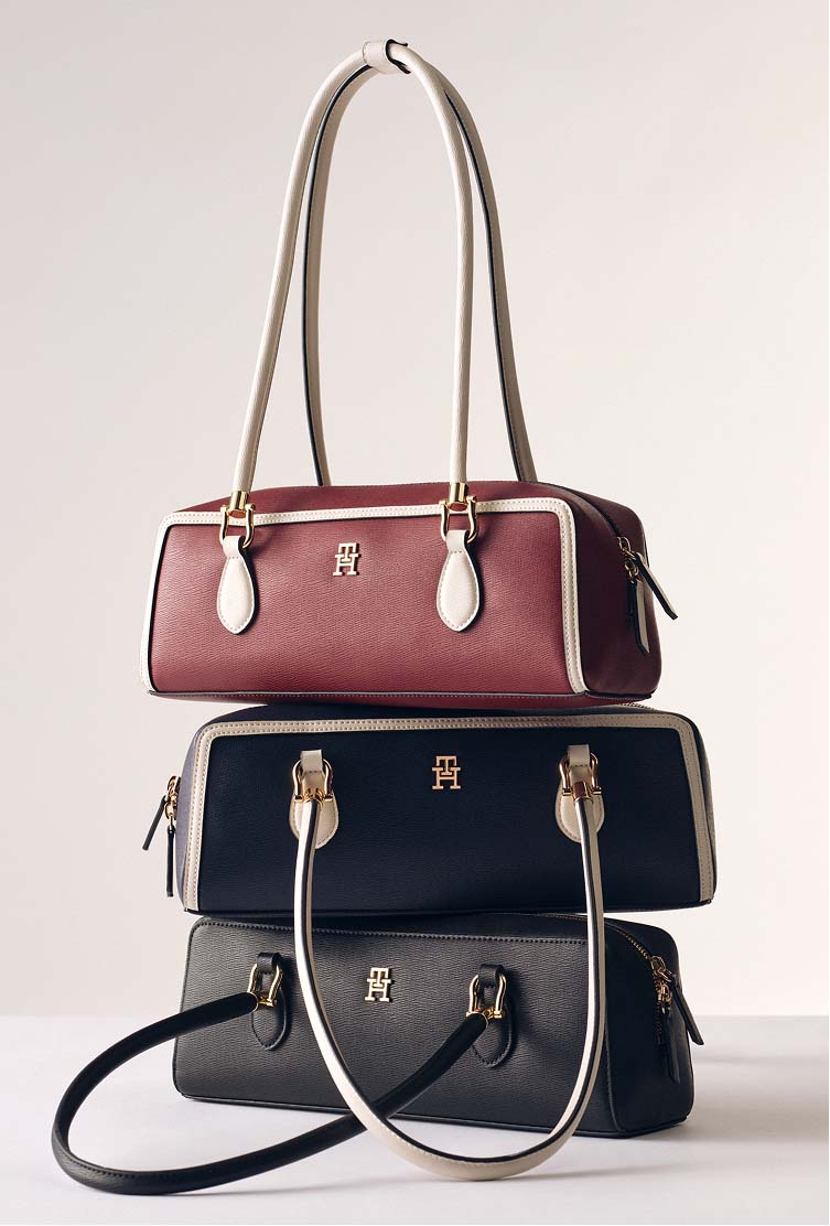 Burgundy and navy Tommy Hilfiger handbags stacked together on a neutral background.