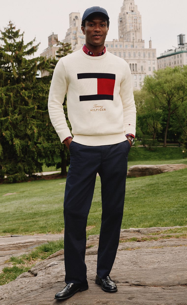 Model standing wearing a Tommy Hilfiger logo sweater.