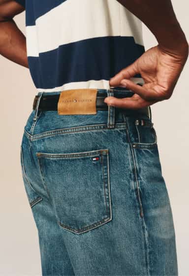 Close-up of the back pocket and waistband of blue denim jeans featuring Tommy Hilfiger branding.