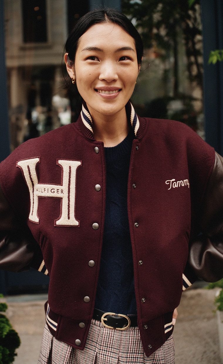 Woman wearing a Tommy Hilfiger burgundy varsity jacket.