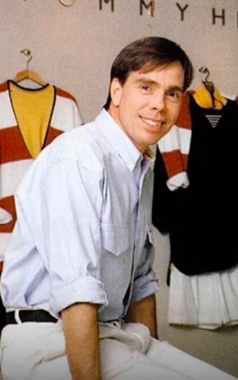 Tommy Hilfiger sitting in front of his outfit designs.