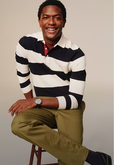 Model wearing a Tommy Hilfiger navy and white striped long-sleeve polo shirt with dark trousers.