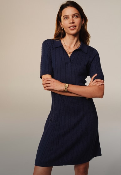 Model standing with wearing a Tommy Hilfiger navy short-sleeve knit dress.