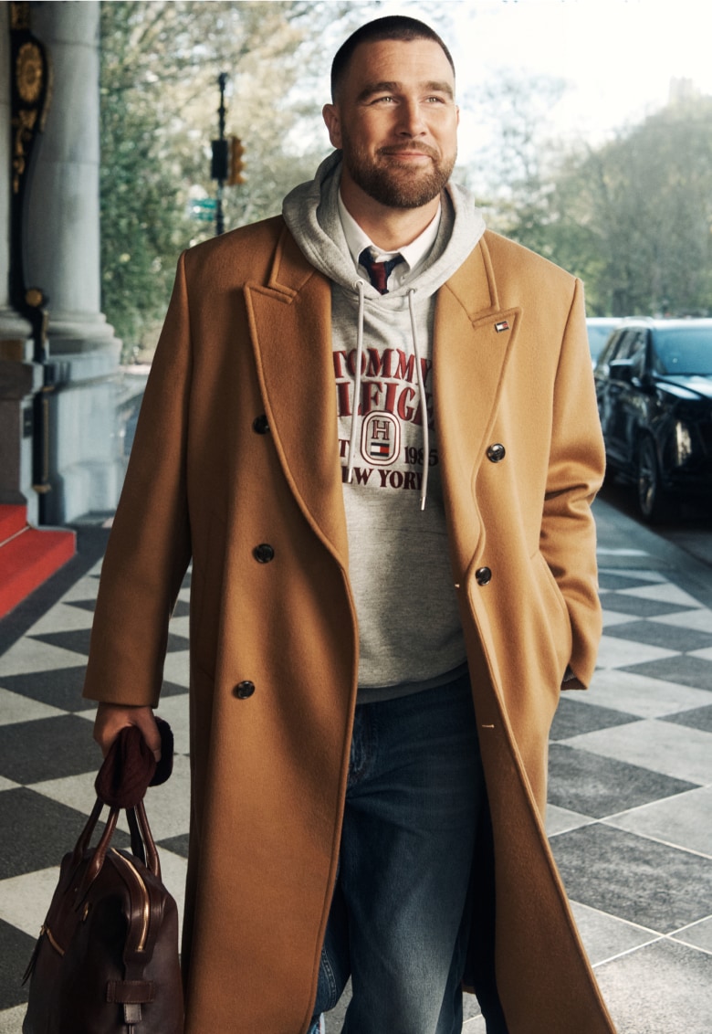 Travis Kelce wearing a long brown peacoat, new from Tommy Hilfiger.