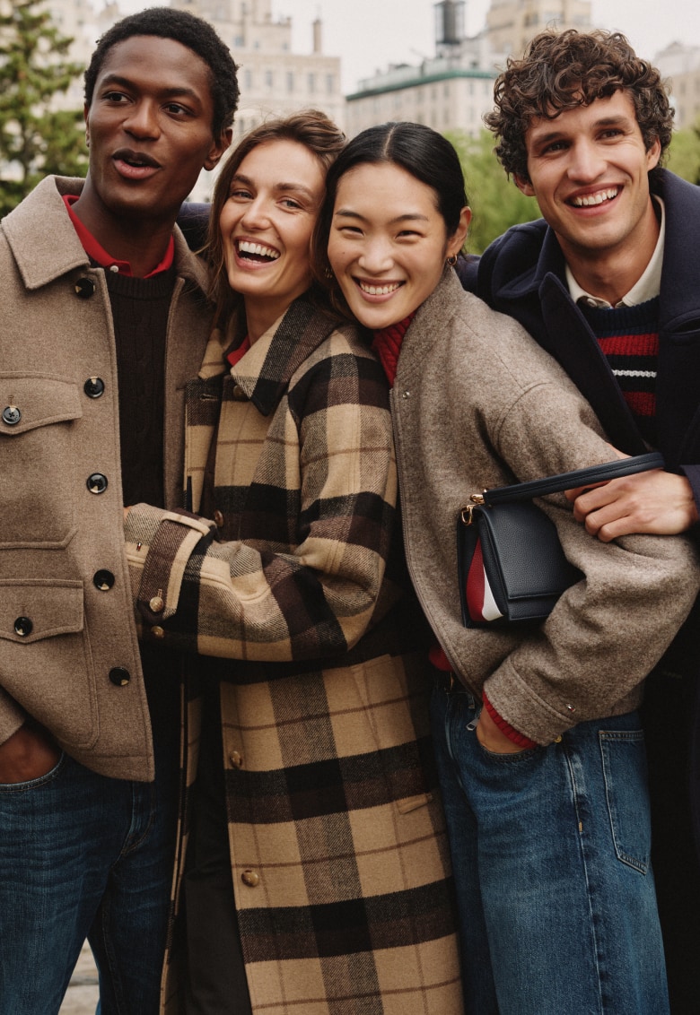 Four models outdoors wearing layered Tommy Hilfiger fall jackets and coats.