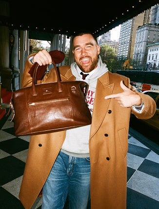 Travis Kelce wearing a Tommy Hilfiger jacket and leather bag in the Plaza Hotel.
