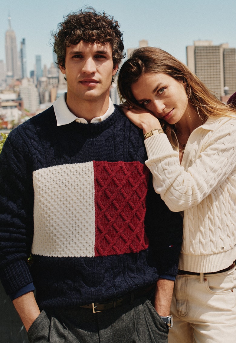 Four models stand together on a rooftop wearing Tommy Hilfiger outfits.